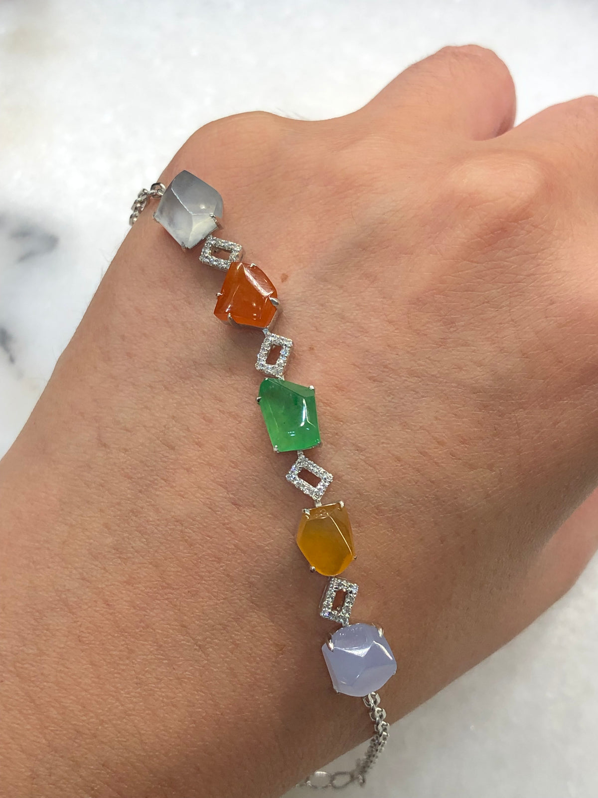 Multi-coloured natural Type A faceted jadeite bracelet featuring green, orange-red, yellow, lavender and icy white jade with diamond-set geometric links in 18K white gold.