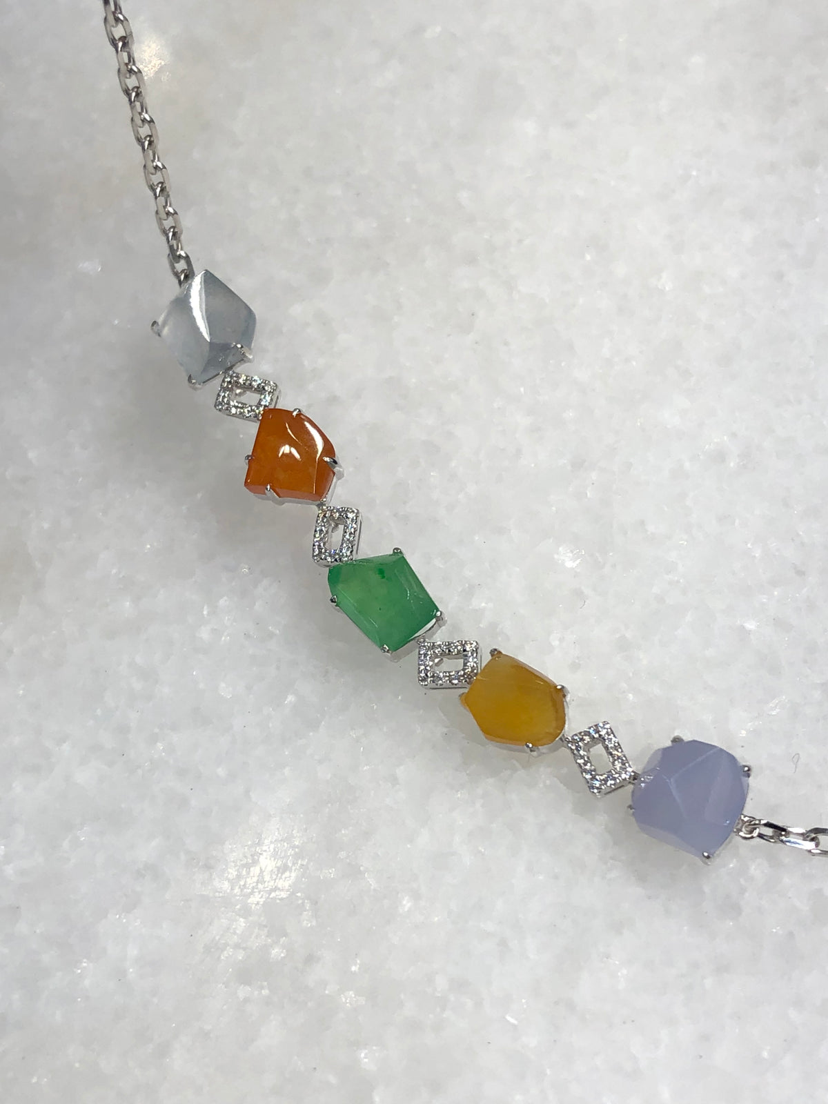 Multi-coloured natural Type A faceted jadeite bracelet featuring green, orange-red, yellow, lavender and icy white jade with diamond-set geometric links in 18K white gold.