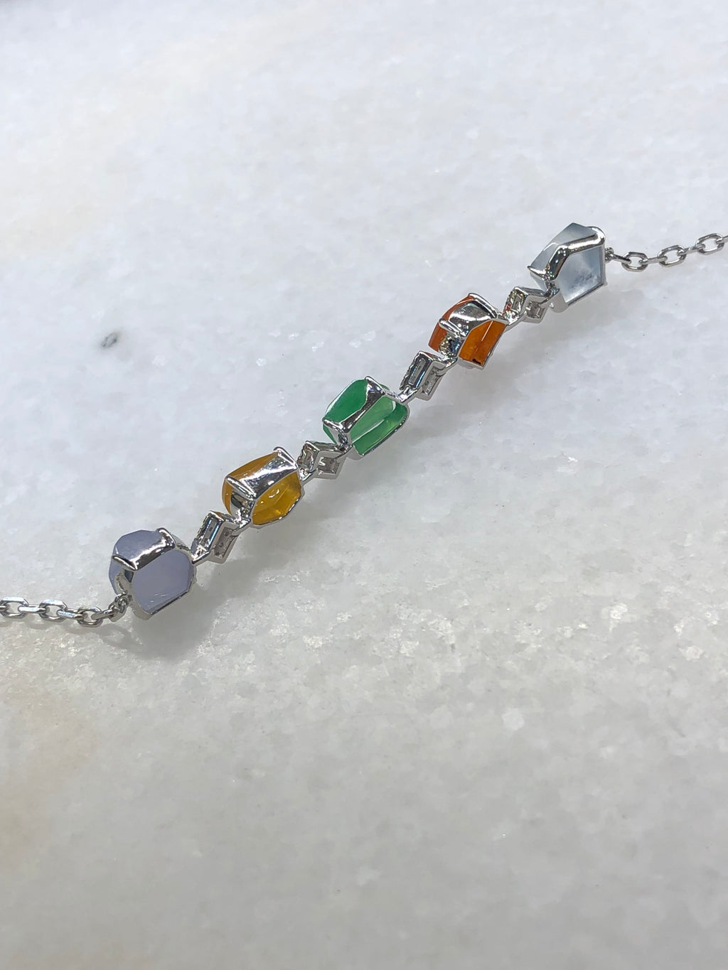 Multi-coloured natural Type A faceted jadeite bracelet featuring green, orange-red, yellow, lavender and icy white jade with diamond-set geometric links in 18K white gold.