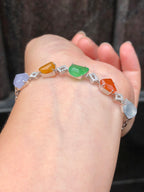Multi-coloured natural Type A faceted jadeite bracelet featuring green, orange-red, yellow, lavender and icy white jade with diamond-set geometric links in 18K white gold.