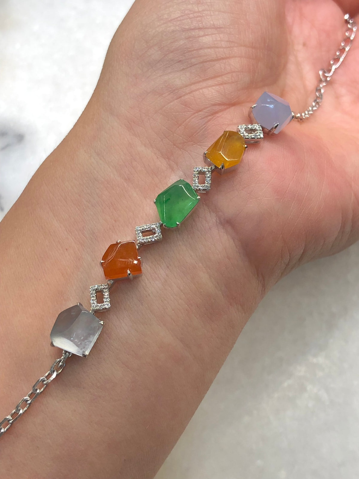 Multi-coloured natural Type A faceted jadeite bracelet featuring green, orange-red, yellow, lavender and icy white jade with diamond-set geometric links in 18K white gold.