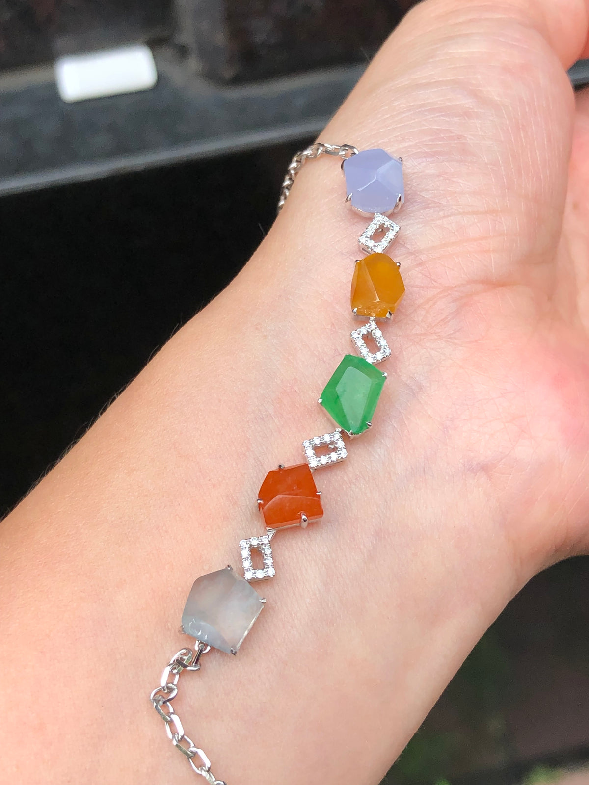 Multi-coloured natural Type A faceted jadeite bracelet featuring green, orange-red, yellow, lavender and icy white jade with diamond-set geometric links in 18K white gold.